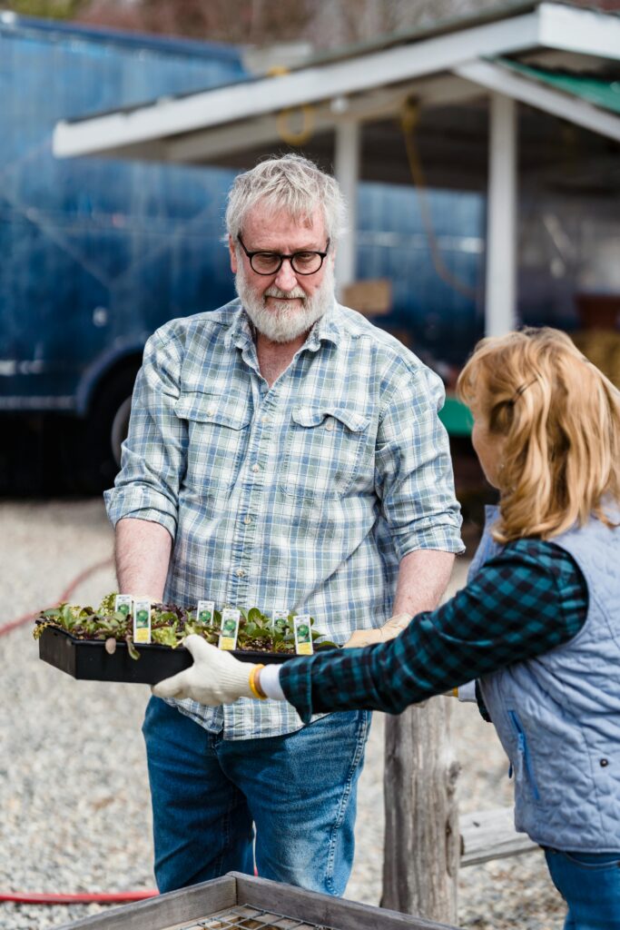 un producteur maraicher proposant des plants à une femme